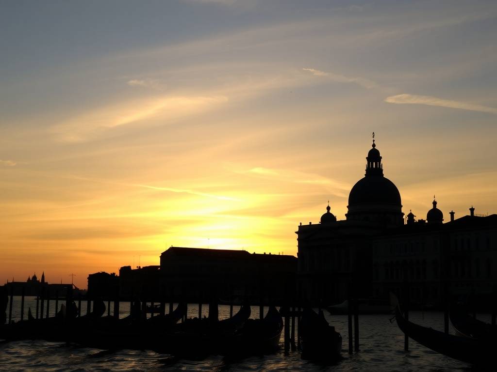 A breathtaking view of a sunset over the Venetian skyline with gondolas in silhouette.